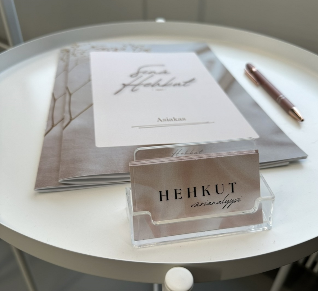 Koulukuva tai päiväkotikuva, jossa nuori tyttö istuu sivullepäin, kylki kohti kameraa. Päällä monivärinen neule, tyttö hymyilee ja katsoo kameraa valloittavasti.  